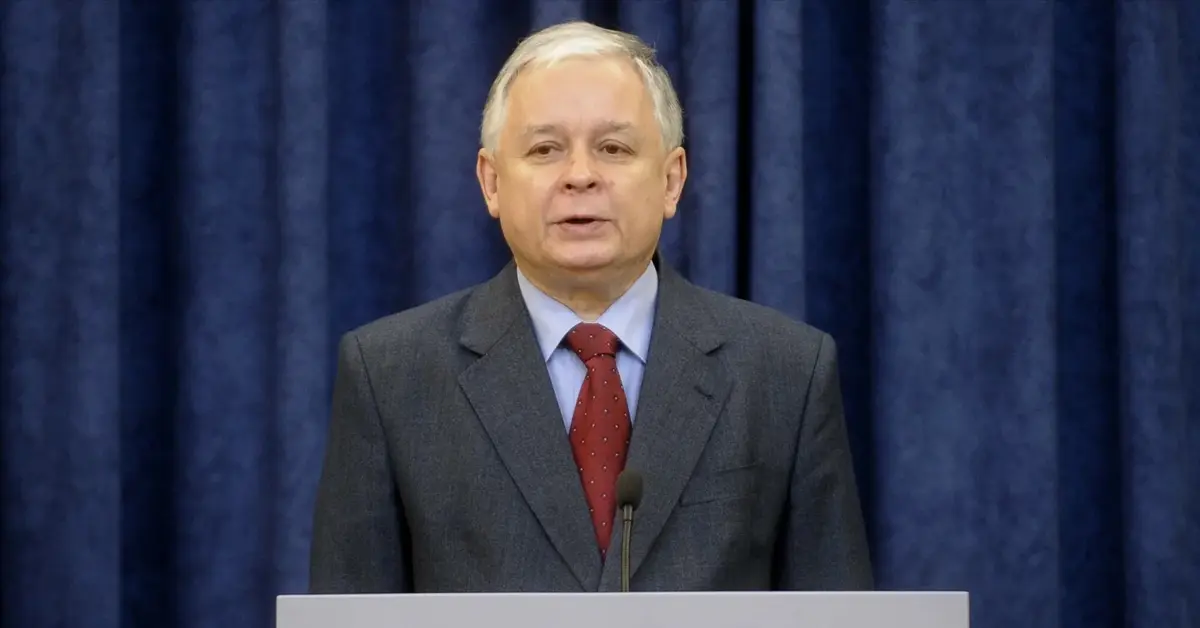 Lech Kaczyński w garniturze stojący za mównicą