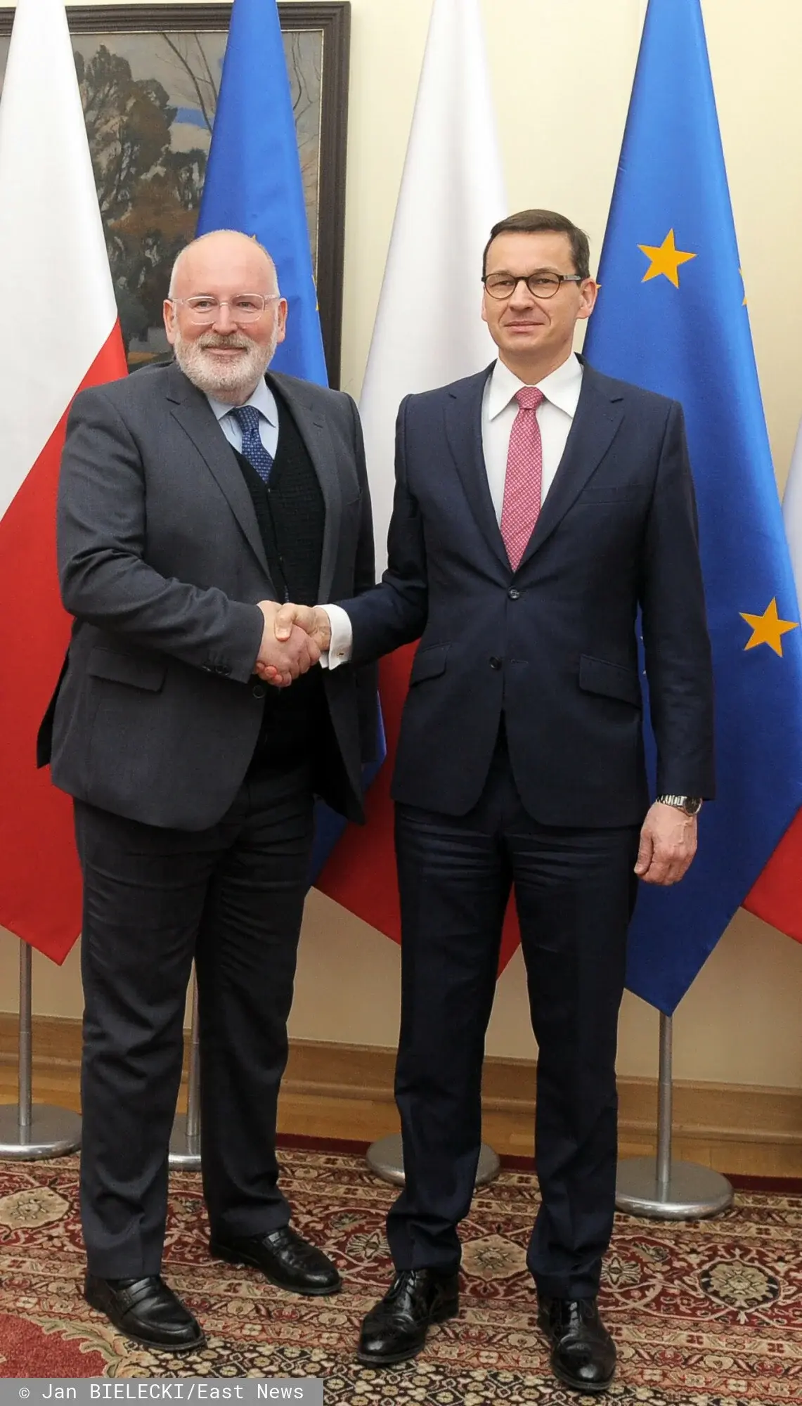 Frans Timmermans na spotkaniu z Premierem Mateuszem Morawieckim na tle flagi Polski i UE