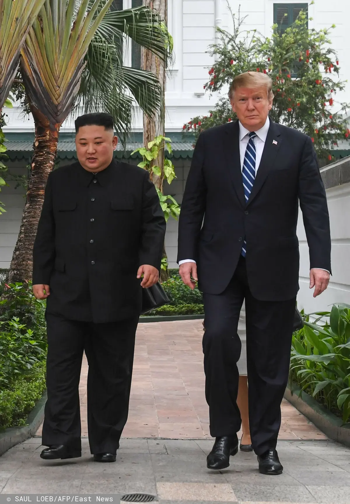 Kim Dzong Un i Donald Trump idący obok siebie podczas przerwy na spotkaniu na szczycie