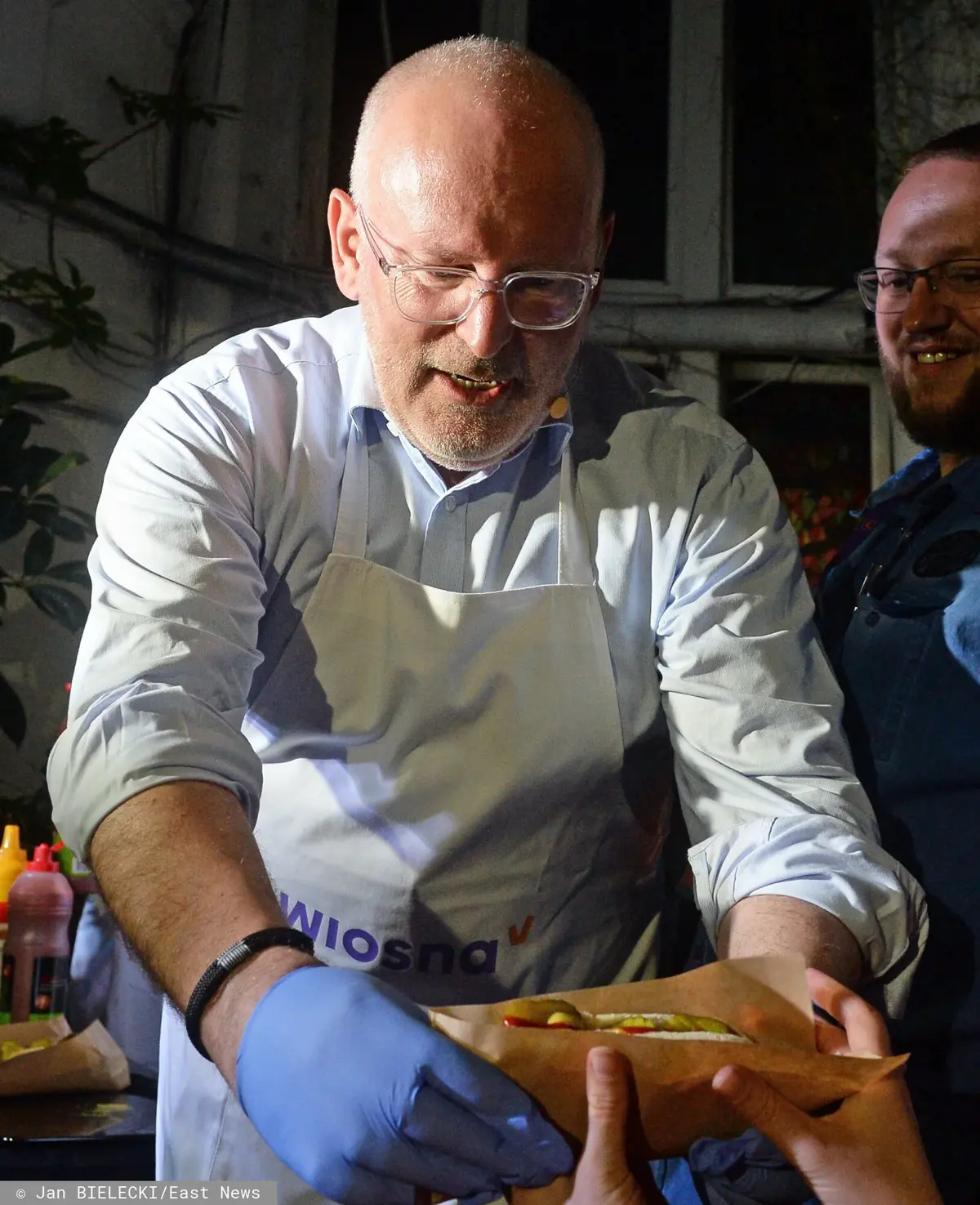 Frans Timmermans rozdający hot-dogi podczas spotkania ("domówki") z Robertem Biedroniem w klubie Miłość