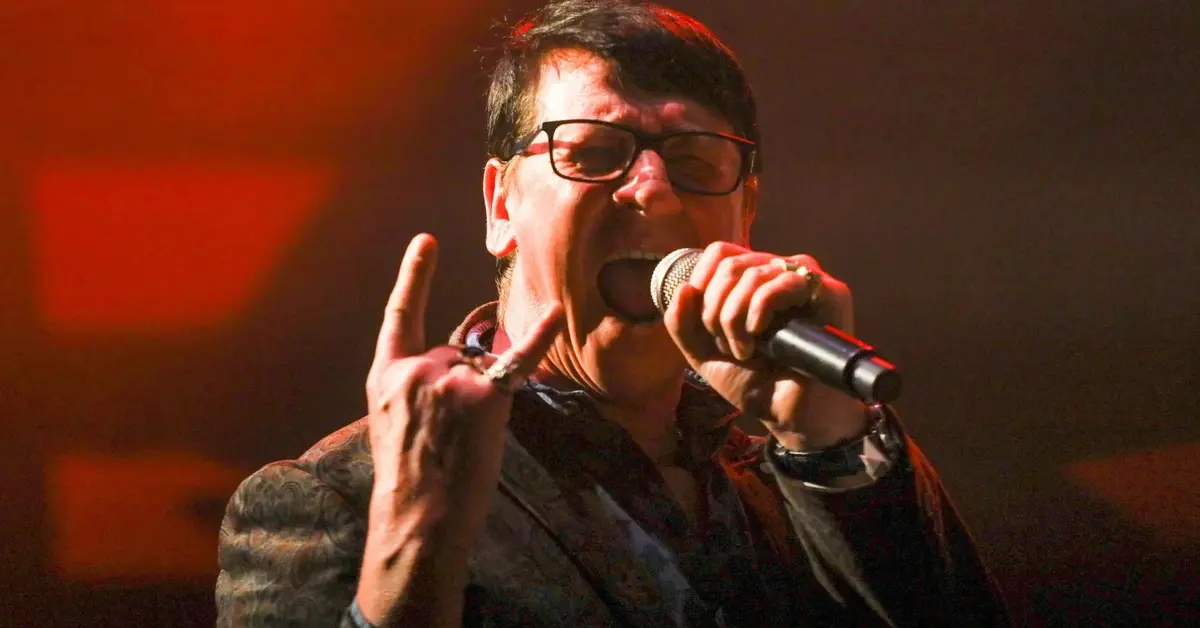 Maciej Maleńczuk krzyczy do mikrofonu, pokazując satanistyczny gest.