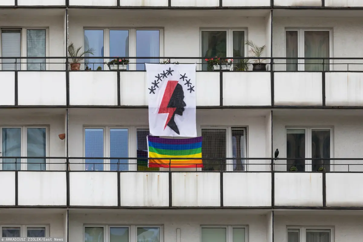 Tęczowa flaga oraz symbol strajku kobiet na balkonie.