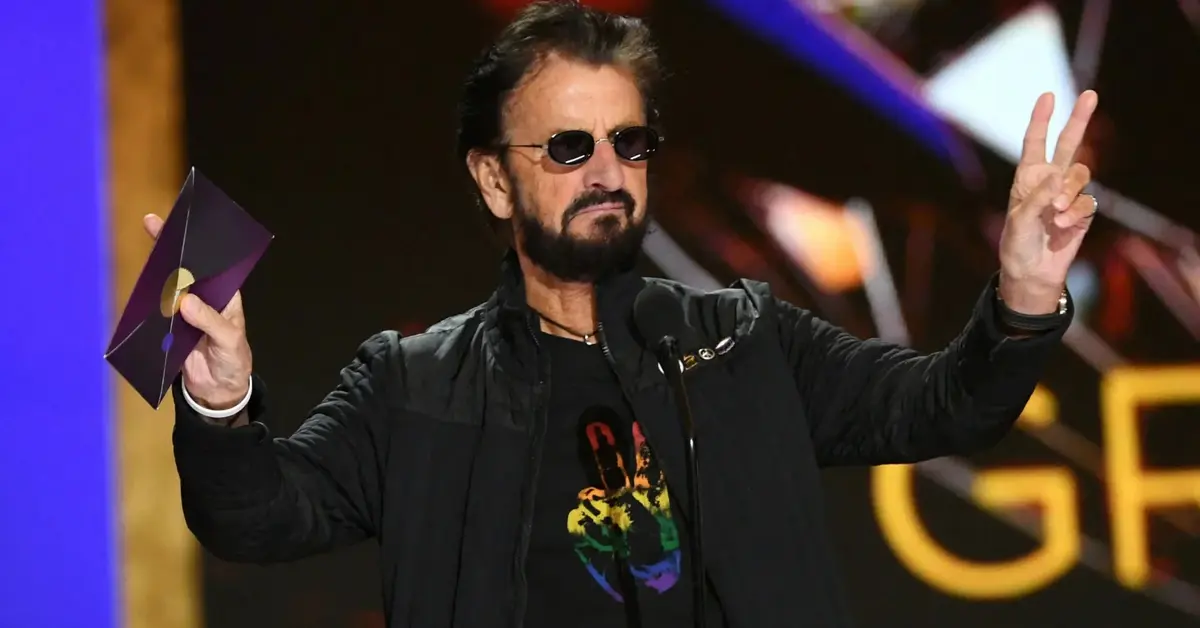 Ringo Starr pokazuje gest pokoju.