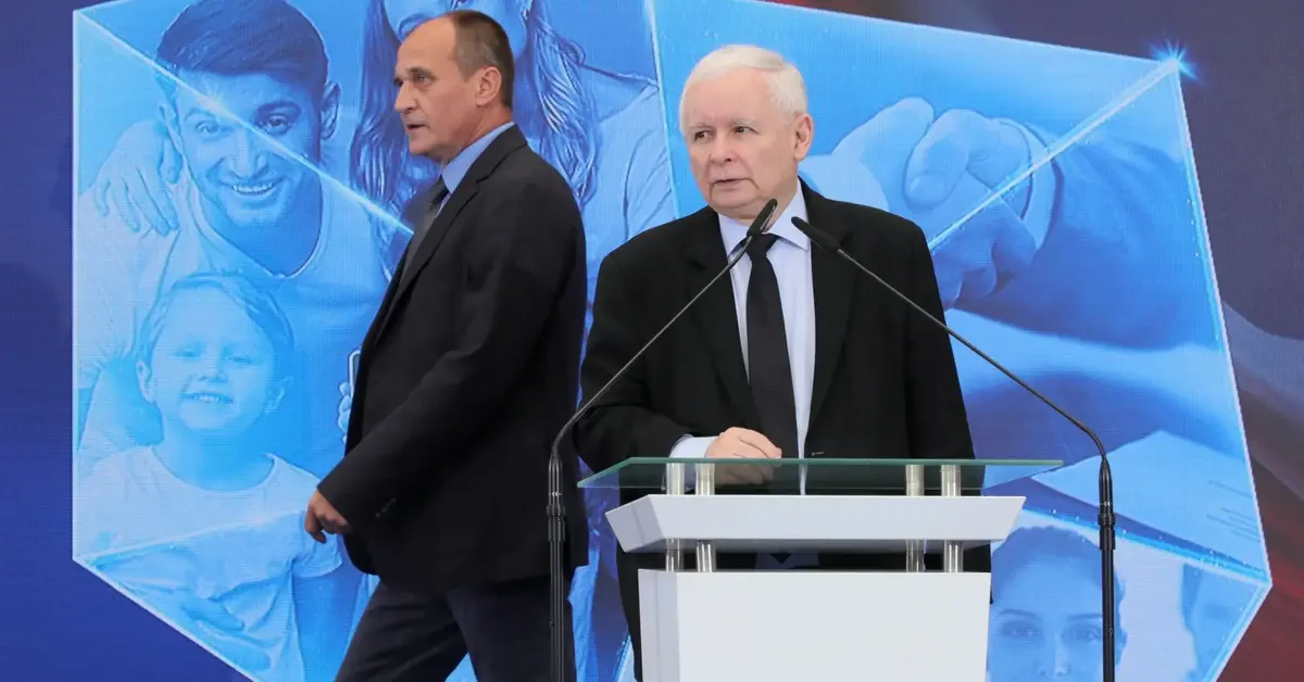 jarosłąw kaczyński przy mównicy, za nim przechodzi paweł kukiz, wszystko na tle konturowej mapy polski