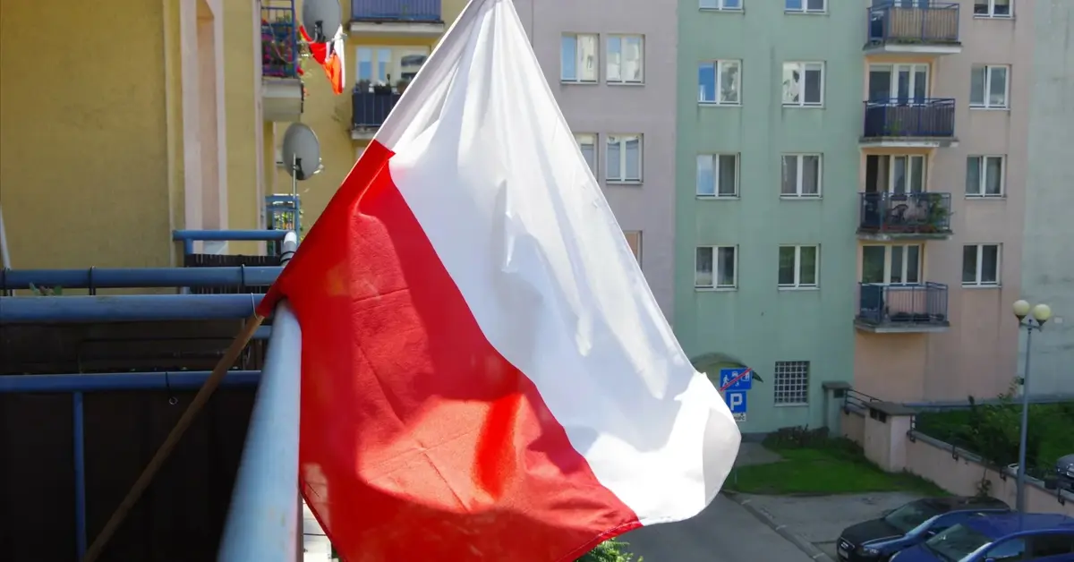 Biało-czerwona flaga Polski wywieszona na balkonie bloku