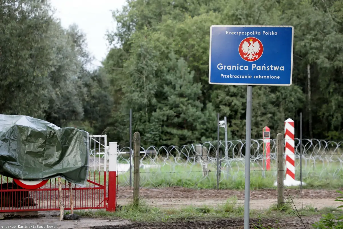 tabliczka z informacją o granicy polsko-białoruskiej i płot z drutem kolczastym