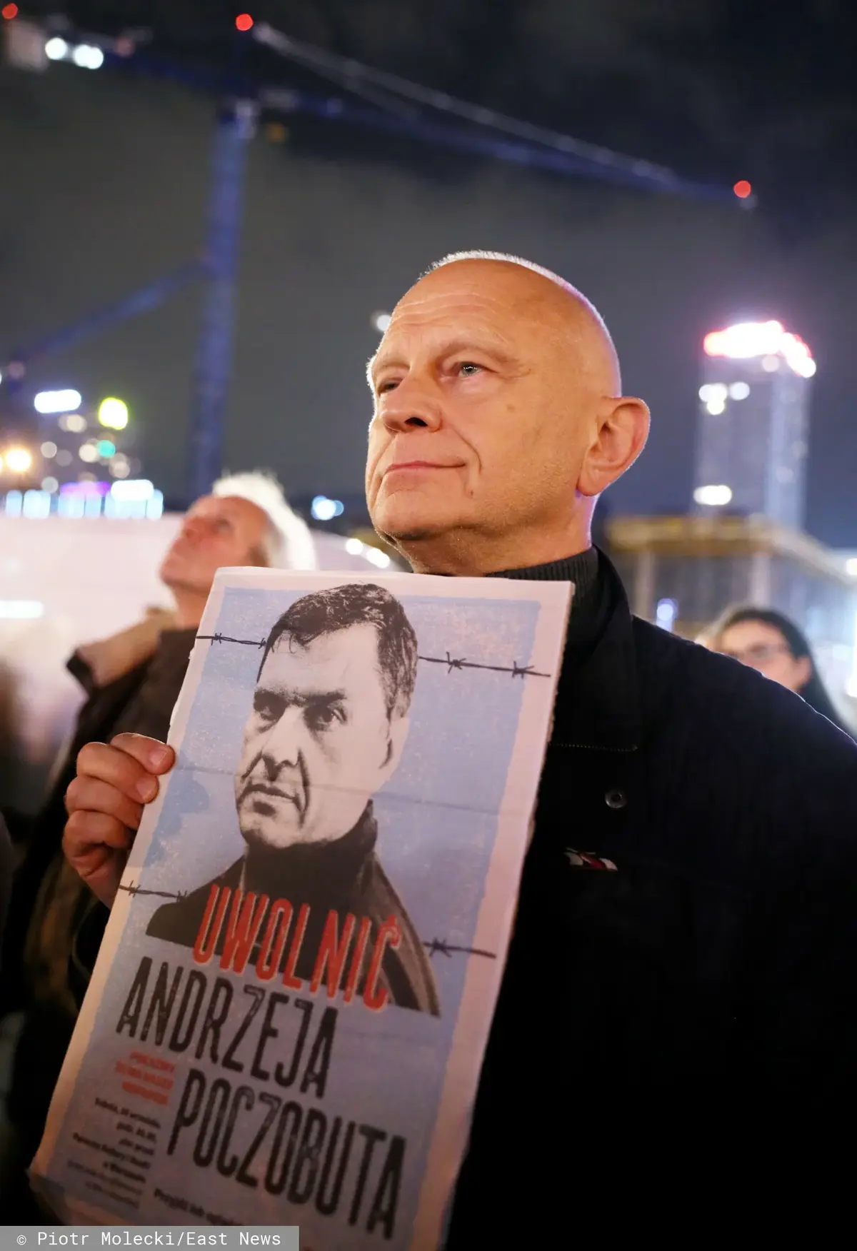 Mężczyzna z plakatem, na którym widnieje Andrzej Poczobut