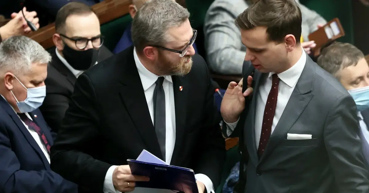 Posłowie Grzegorz Braun i Jakub Kulesza rozmawiający ze sobą w sali plenarnej Sejmu