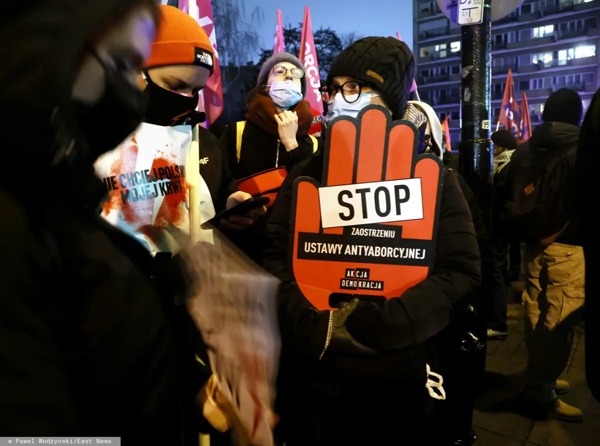 Mężczyzna stojący z plakatem "Stop aborcji" w kształcie dłoni 