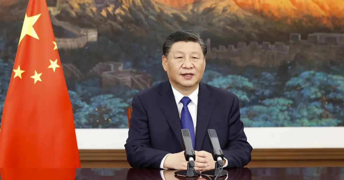 Xi Jinping siedzi w towarzystwie chińskiej flagi.