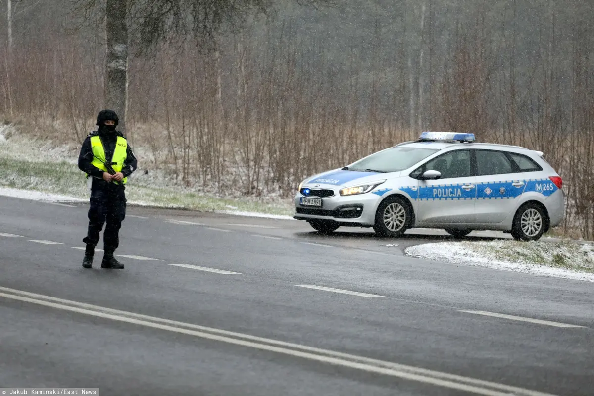policjant stojący na drodze obok samochodu