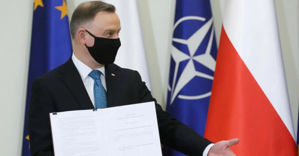 Andrzej Duda w maseczce trzyma podpisane porozumienie.