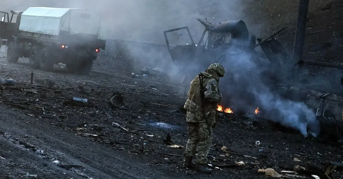 żołnierz ogląda dymiące się miejsce wybuchu 