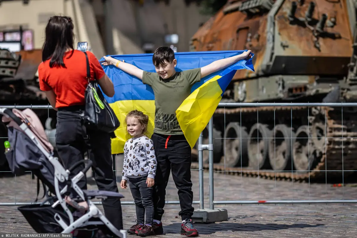 dzieci pozujące z ukraińską flagą