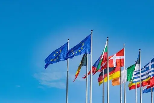 Dwie flagi UE oraz inne flagi państw przynależących do Unii na tle nieba