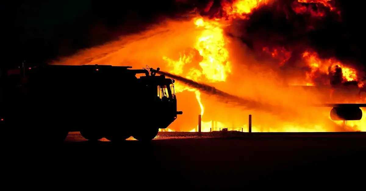 wóz gaśniczy gasi buchające w tle płomienie 