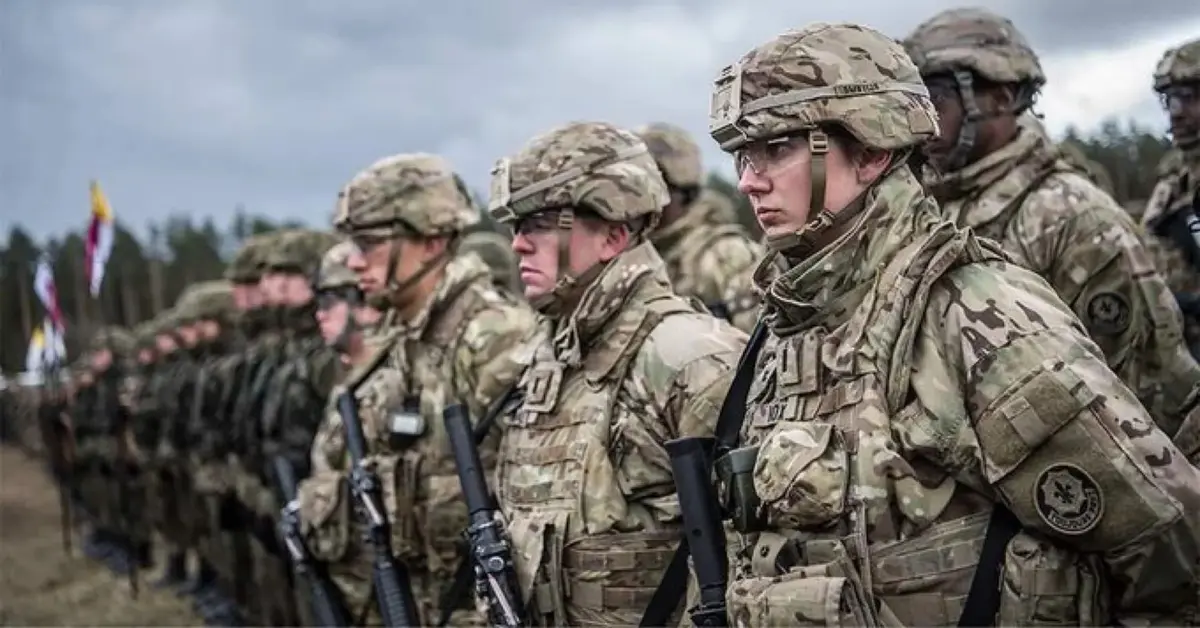 gruoa amerykańskich żołnierzy w mundurach polowych z bronią stojąca w równym rzędzie na poligonie