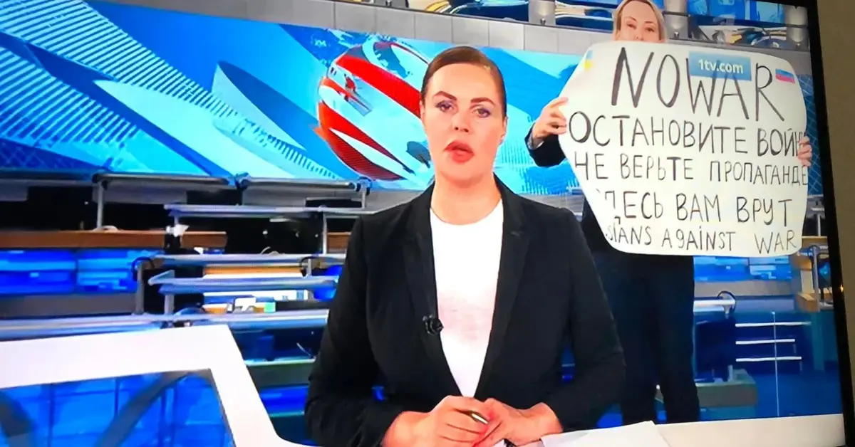 prezenterka rosyjskiej telewizji, a za jej plecami osoba z antywojennym sloganem na planszy