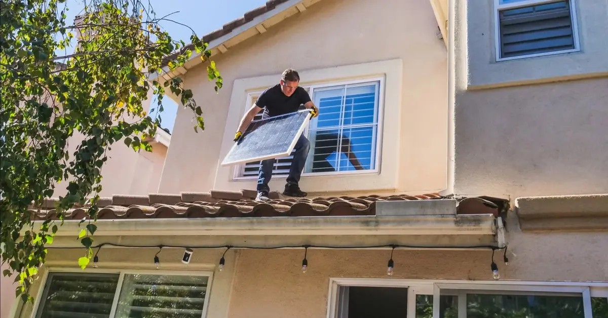 Mężczyzna montuje panele fotowoltaiczne na dachu