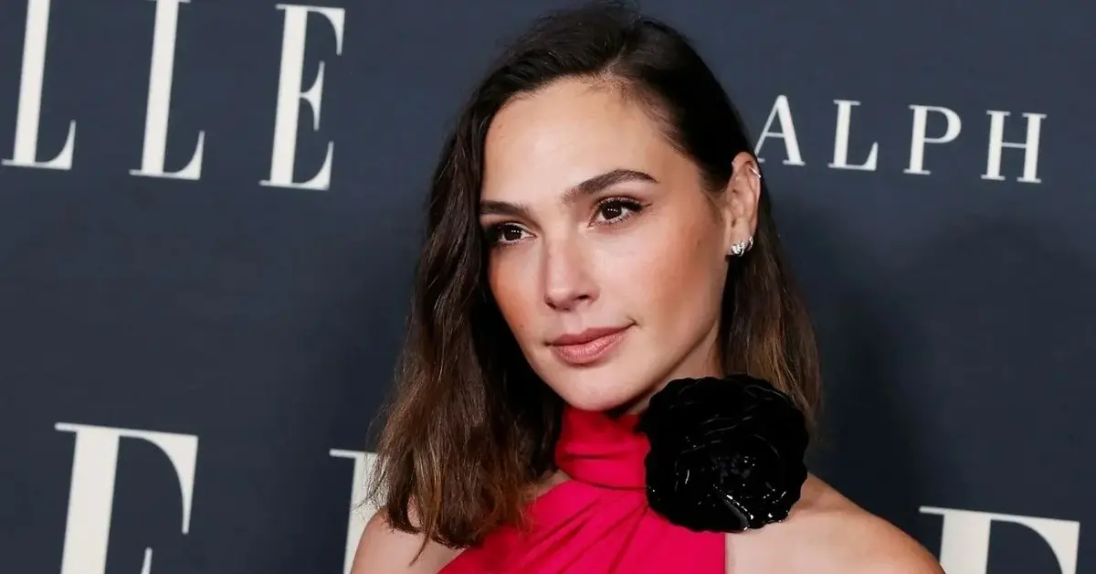 Gal Gadot w czerwonej sukience z czarną różą na tle czarnej ścianki podczas 27. nagród Elle Women in Hollywood