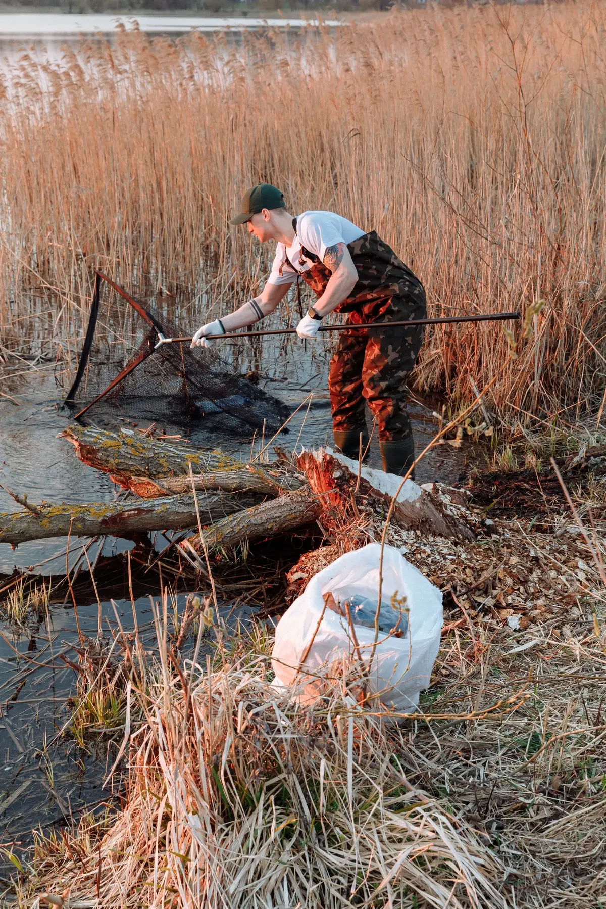 Mężczyzna wyławia śmieci z rzeki przy użyciu podbieraka