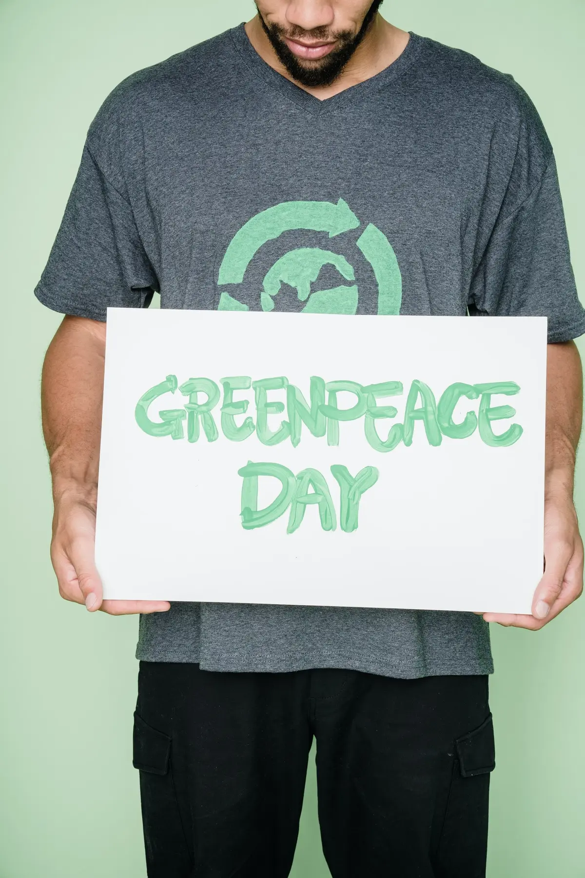 Mężczyzna trzyma kartkę z napisem "Greenpeace Day"
