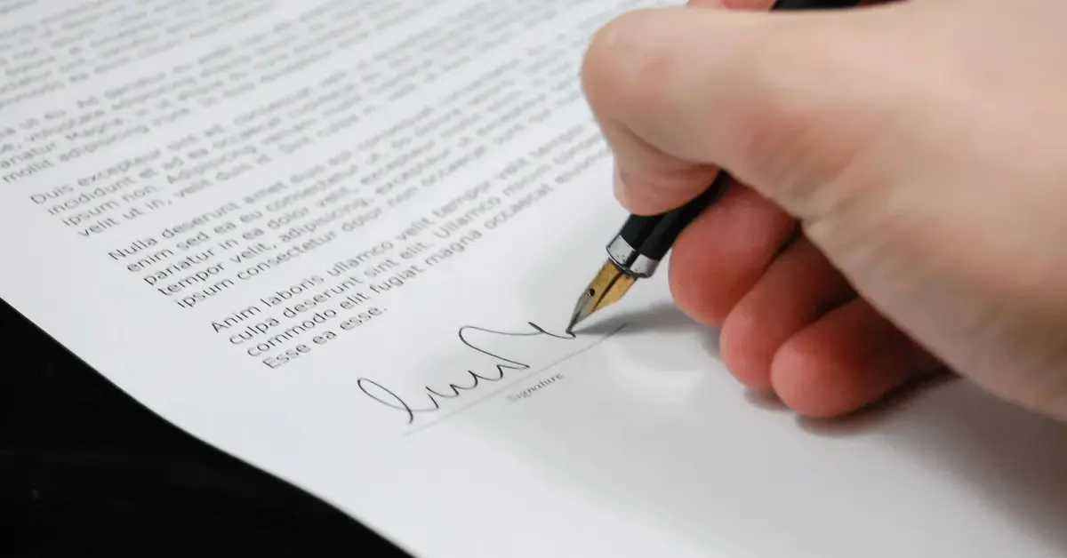 Dłoń z piórem, podpisująca dokument