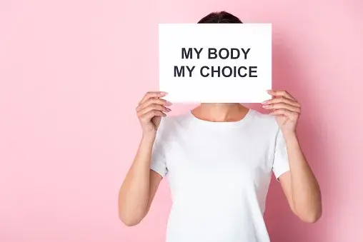 Kobieta w białym T-shircie z kartką z napisem „My body My choice" 