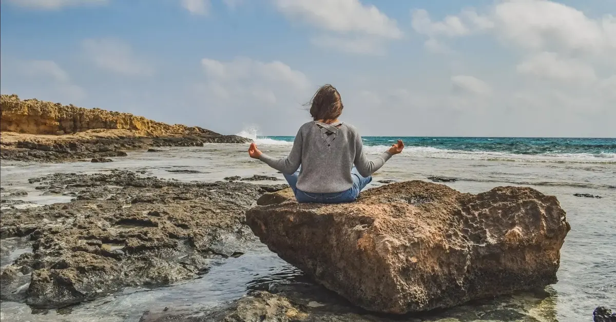 Medytująca kobieta siedząca na kamieniu 