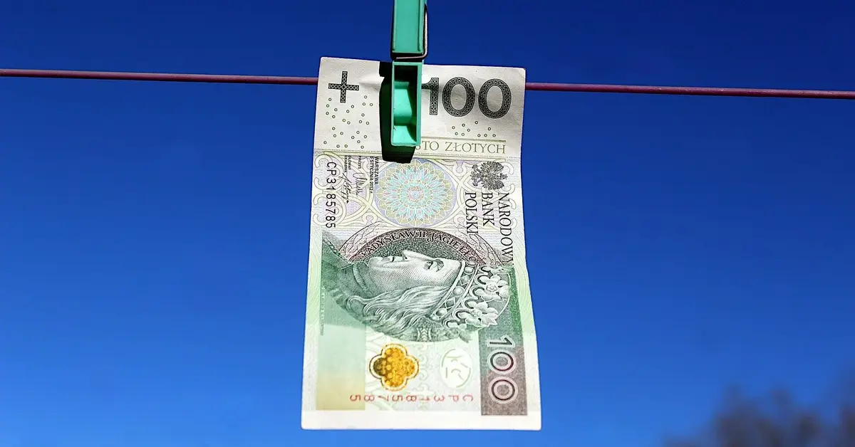 banknot 100 zł wiszący na sznurku przypięty spinaczem do bielizny