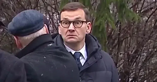 mateusz morawiecki w płaszczu z bardzo dziwną miną