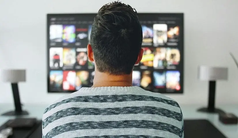 Mężczyzna wpatruje się w aplikację Netflix na telewizorze