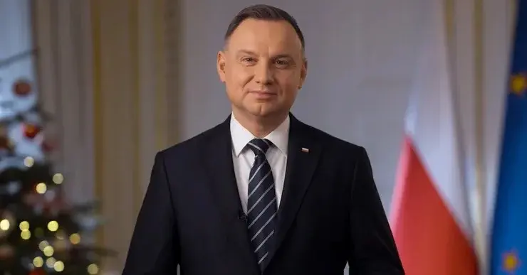 Andrzej duda przemawia w orędziu obok choinki i flag Polski oraz Unii