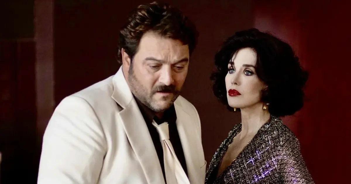 Denis Ménochet w białym garniturze i Isabelle Adjani w błyszczącej sukni na bordowym tle