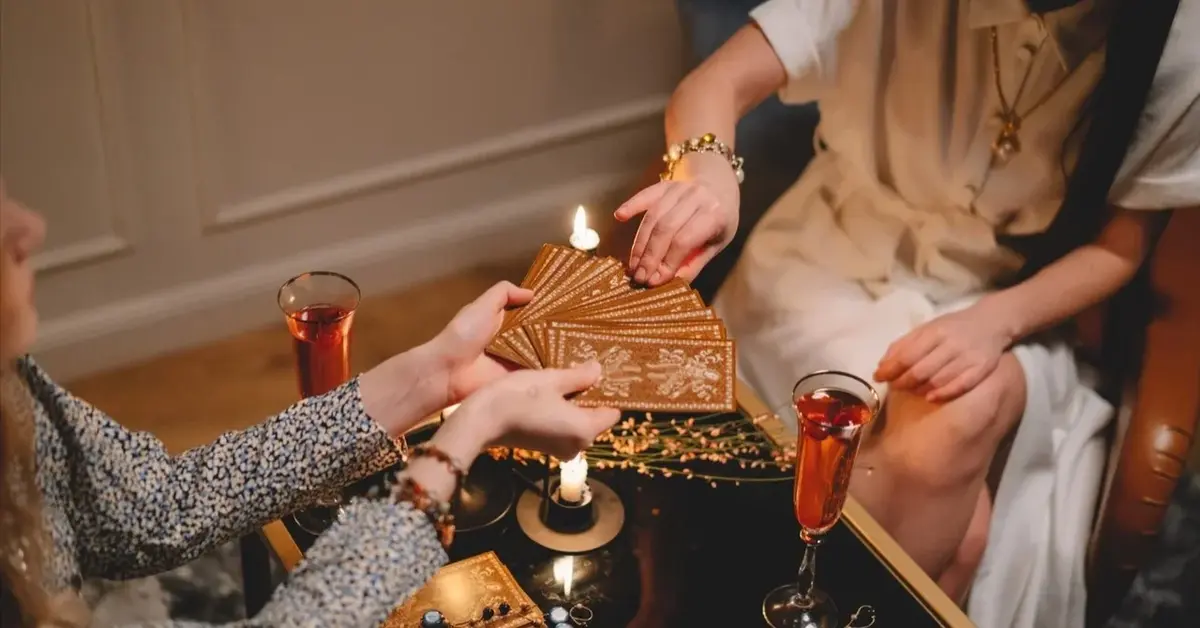 Kobiece dłonie losujące karty na tle świeczek