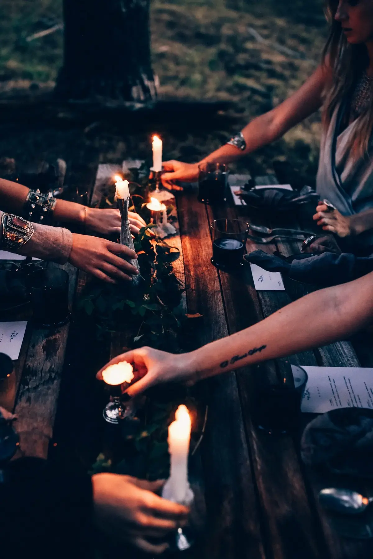 Kobiece ręce trzymające zapłon świeczki na tle ciemnego, podłużnego drewnianego blatu