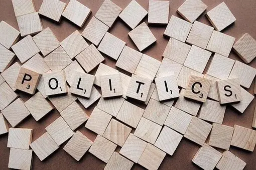 Napis „Politics" ułożony na drewnianych płytkach
