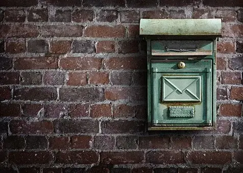Staromodna skrzynka pocztowa w kolorze zielonym na tle ściany z cegieł