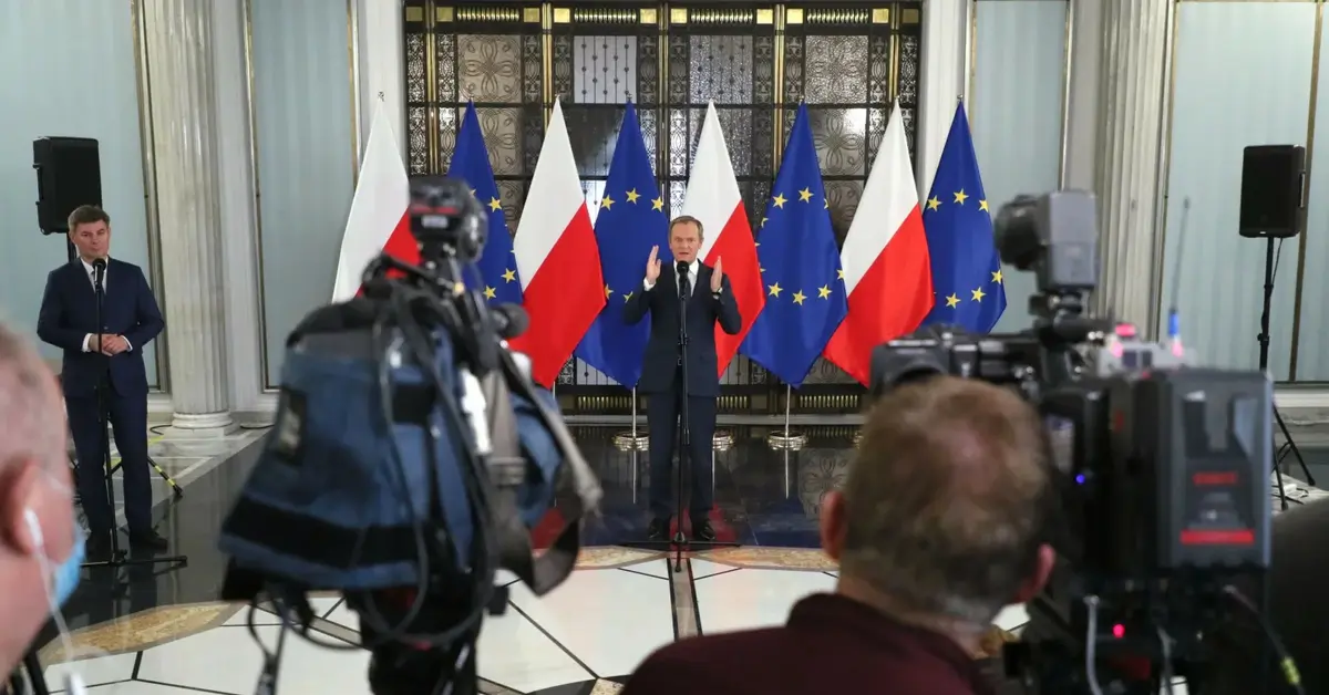Donald Tusk w tle flagi Polski i UE