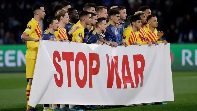 Piłkarze Barcelony i Napoli przy transparencie z napisem STOP WAR