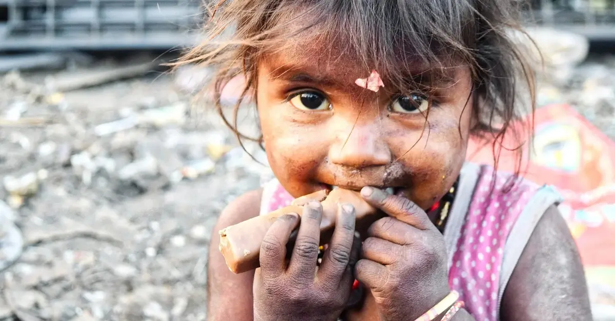 niezwykle brudna dziewczynka uśmiecha się, jedząc cos brudnymi rękami