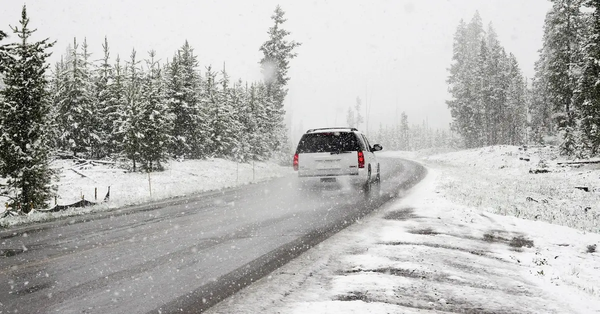samochód jadący zaśnieżoną drogą