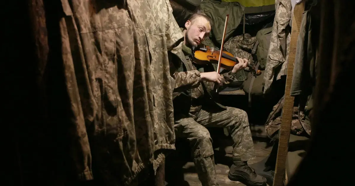 Ukraiński żołnierz gra na skrzypcach w okopie