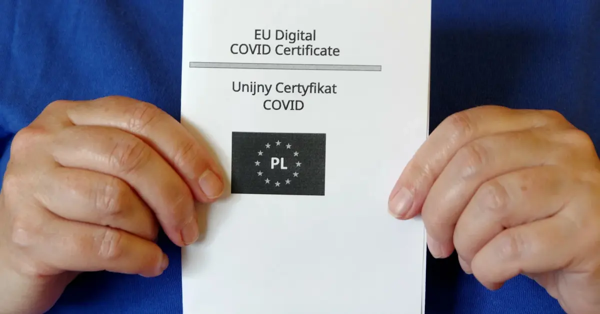 Unijny Certyfikat COVID trzymany w rękach