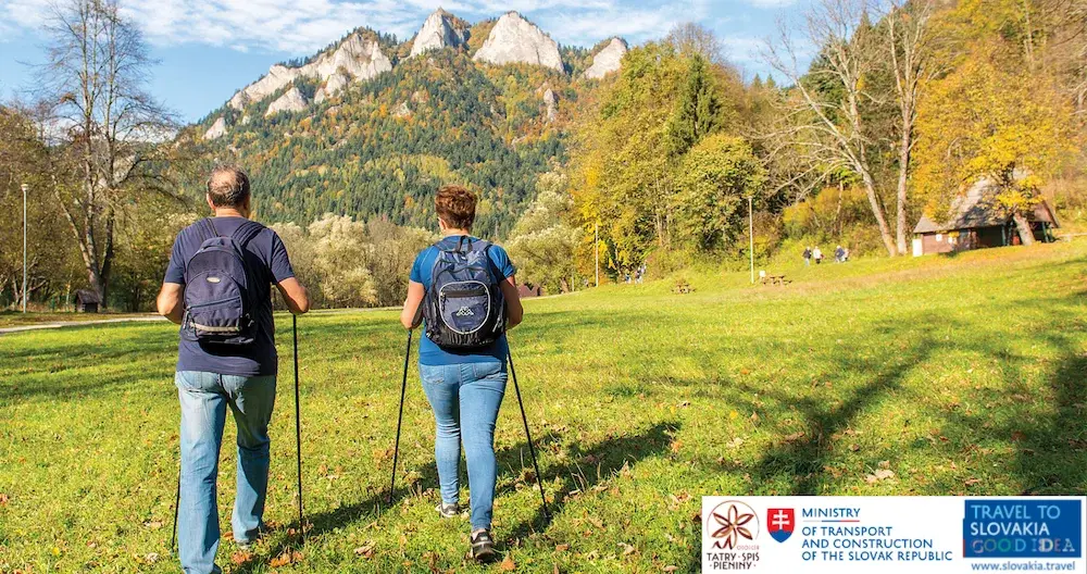 Para turystów wędruje pieszo z kijkami piękną doliną górską w tle góry Region Tatry - Spisz - Pieniny