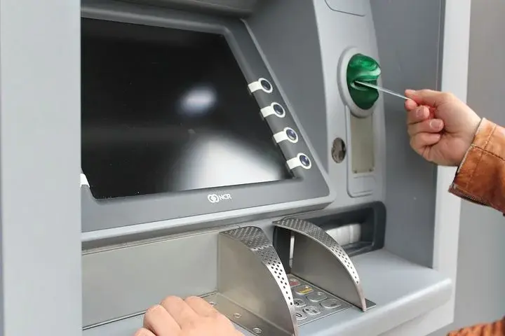 Mężczyzna wkłada kartę do bankomatu/wpłatomatu