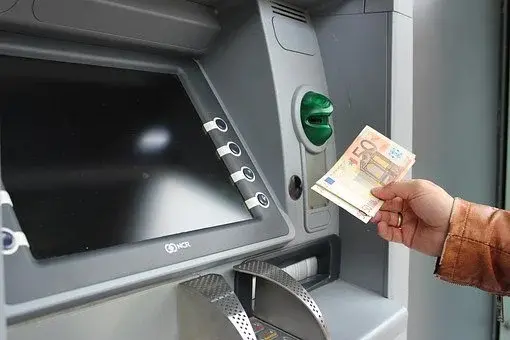 Mężczyzna trzyma gotówkę w ręce przy bankomacie