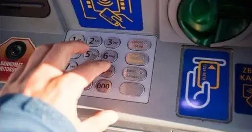 Mężczyzna wpisuje PIN na klawiaturze numerycznej bankomatu