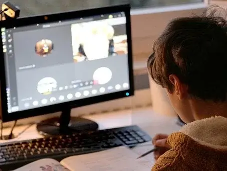 Chłopiec siedzi przed komputerem, uczy się, wykonuje zadania